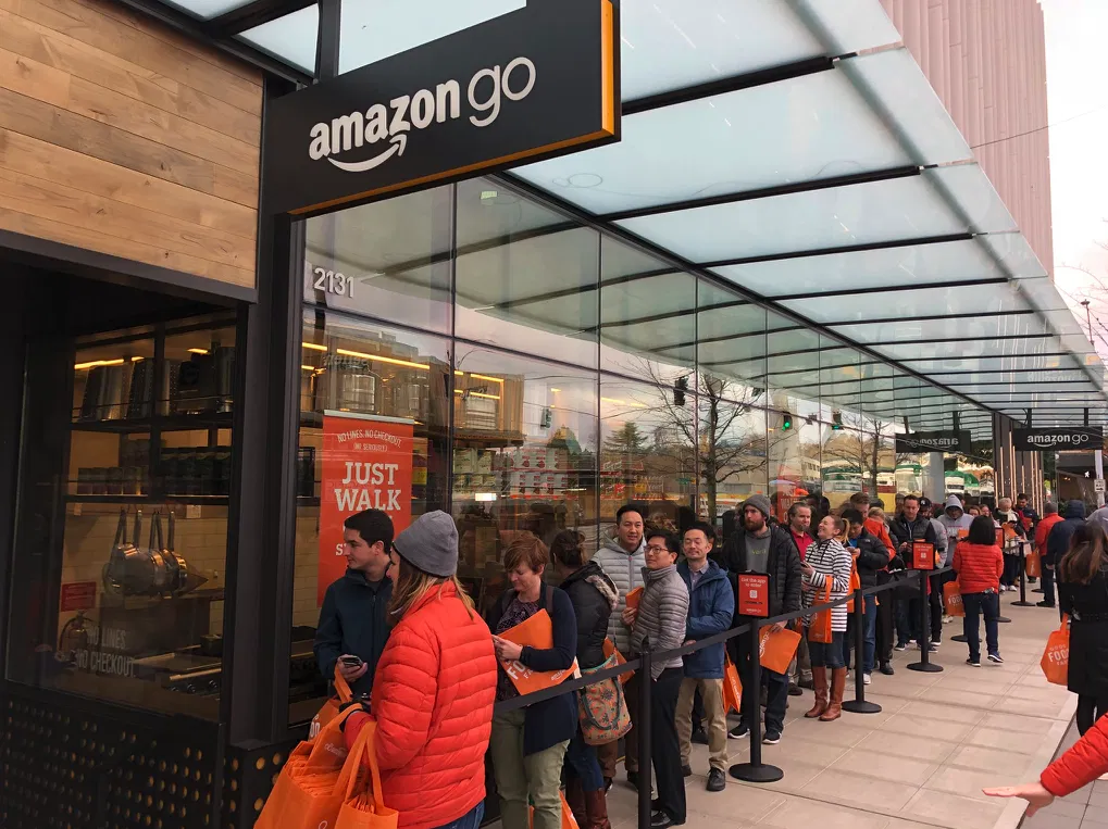 La photo montre une longue file d'attente de personnes souhaitant découvrir l'un des premiers magasins sans caisse d'Amazon GO. La photo montre une longue file d'attente de personnes souhaitant découvrir l'un des premiers magasins sans caisse d'Amazon GO.